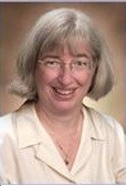 Professional Headshot of woman in business casual collared shirt. Plain brown backdrop in the background.