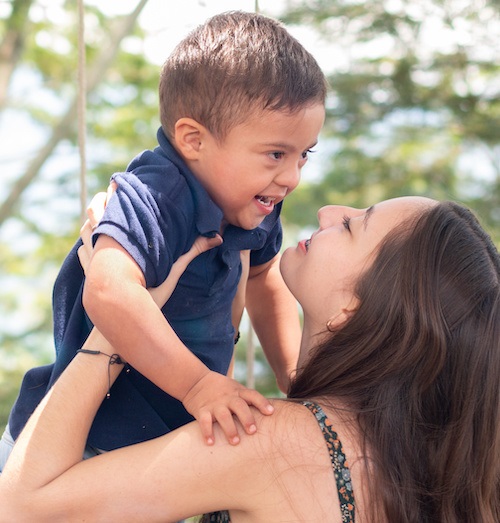 Mother holding young child with Down syndrome