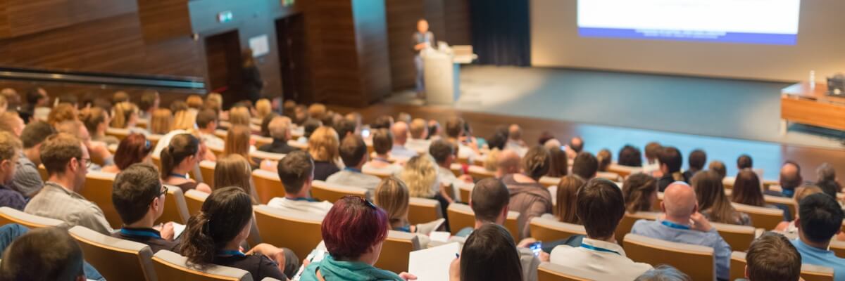 Audience of people watching presenter in auditorium