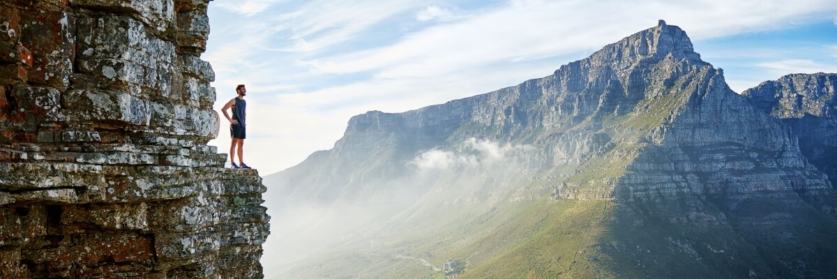Man standing on cliff looking over a valley