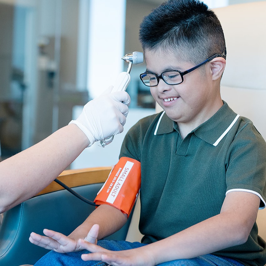 Clinical coordinator taking the vitals of a research participant with Down syndrome
