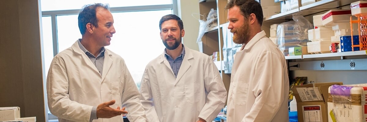 Scientists in lab coats talking in the lab