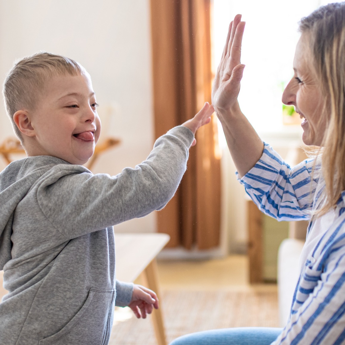 Woman high-fiving young boy with Down syndrome
