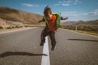 ADHD - Photo by Alvin Mahmudov on Unsplash Young boy jumping in the middle of a road in the mountains.